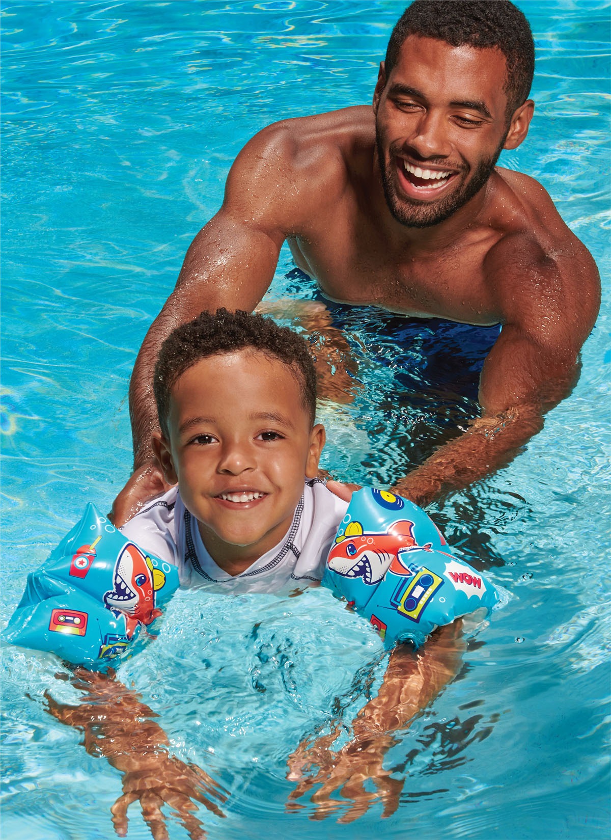 Lifestyle product photography: Man and son, son wearing inflatable pool float arm bands
